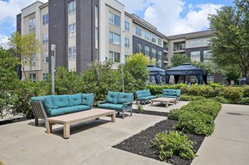 A modern outdoor seating area with blue cushioned sofas and a black umbrella.